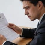 homme inquiet assis au bureau regardant contrats assurance