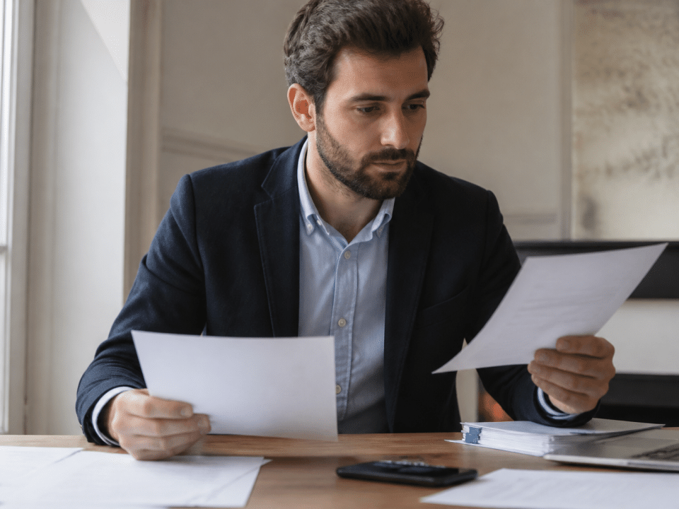 Entrepreneur assis a son bureau tenant documents creation entreprise