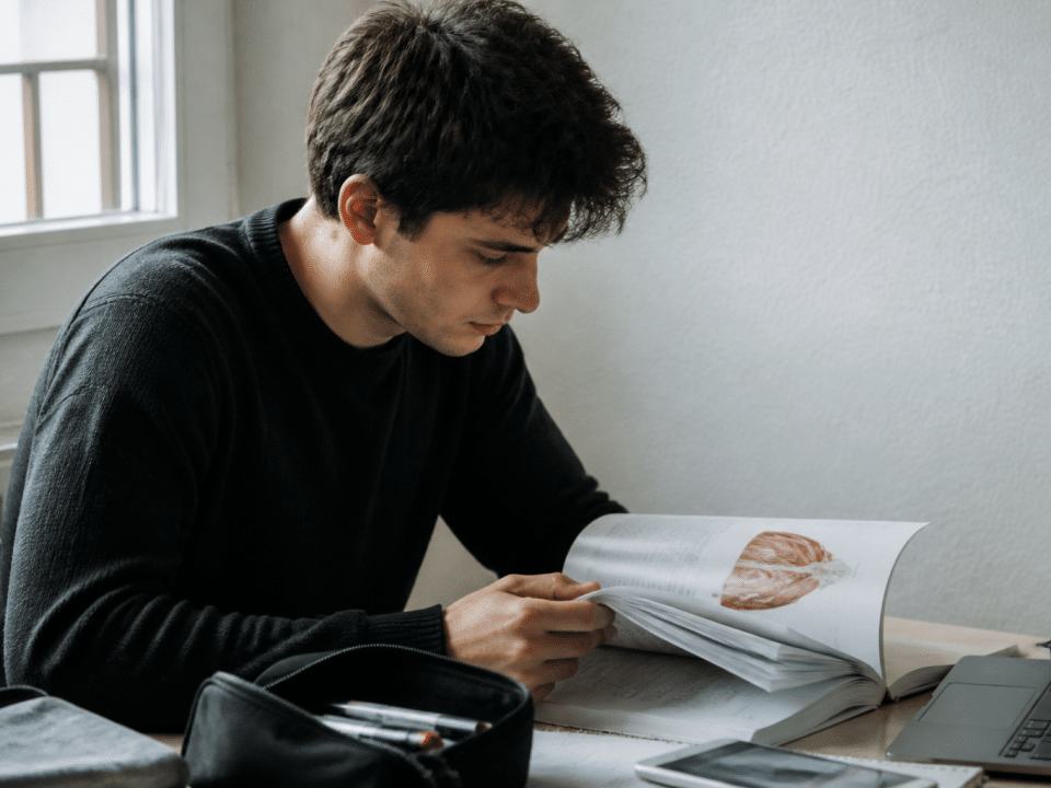 Etudiant assis a un bureau consultant documents formation osteopathie