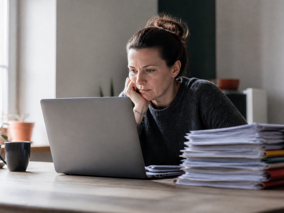 Personne assise devant ordinateur portable, documents formation empiles a cote