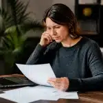 Femme assise a table consultant documents financiers importants seule