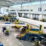 Vaste usine moderne aux murs blancs surplombant chaîne assemblage avions