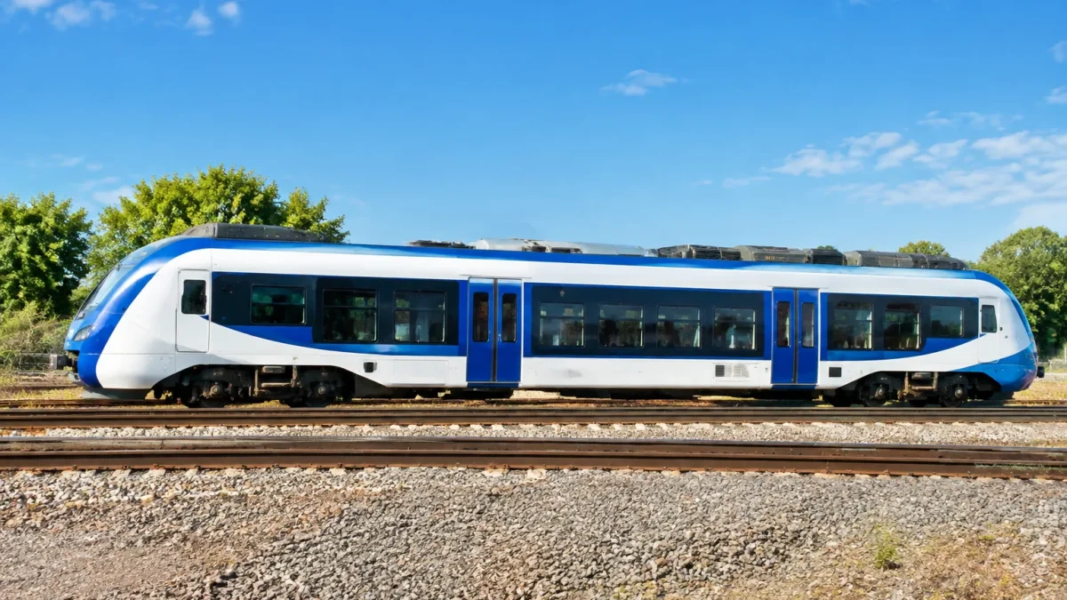 Train blanc et bleu stationnant sur rails, vue de côté complète