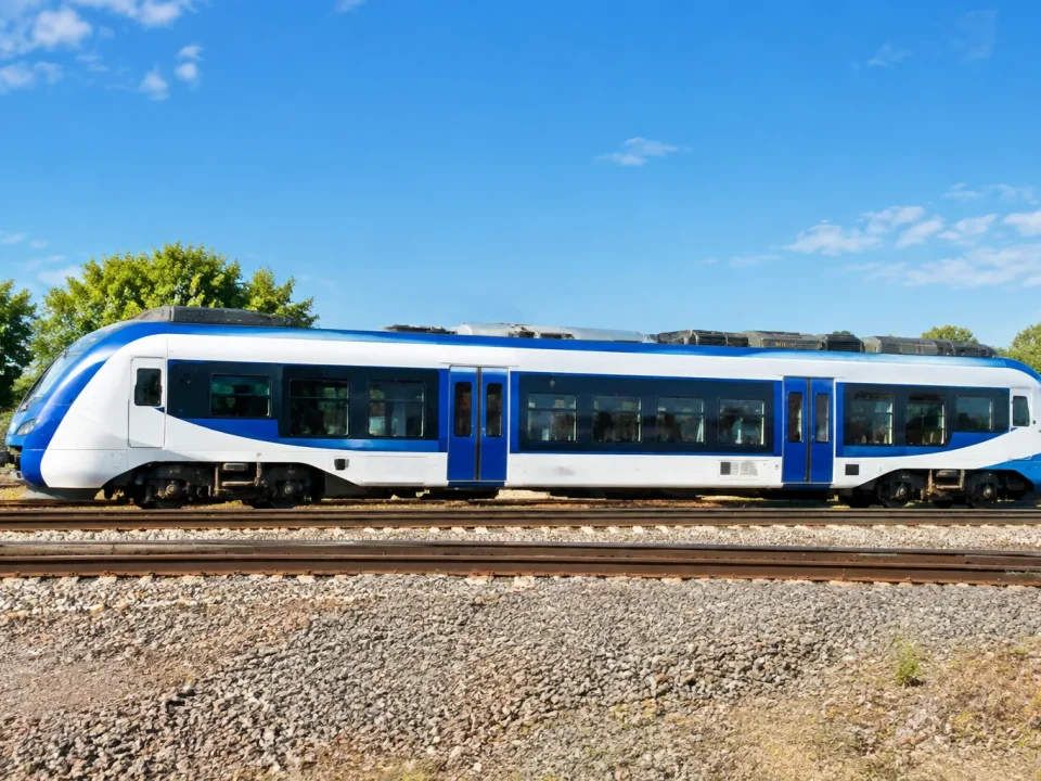 Train blanc et bleu stationnant sur rails, vue de côté complète