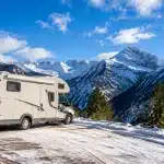 Camping-car stationne face aux montagnes enneigées espagnoles l'hiver