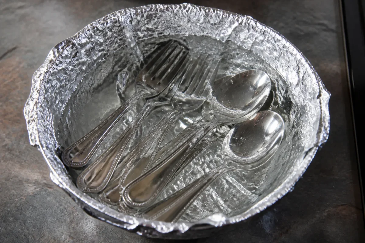 Couverts trempes dans eau chaude avec feuille aluminium