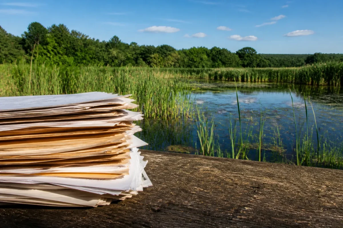 Documents administratifs empiles devant zone humide
