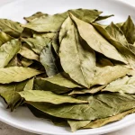 Feuilles laurier seches etendues sur plateau blanc