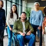 Groupe de personnes debout dans bureau administratif, certaines utilisant cannes ou fauteuils roulants
