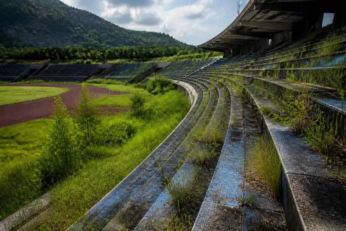 Stades abandonnés avec structures vides et herbe envahissante