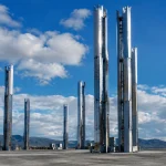Installations metalliques enormes s'elevent verticalement sur terrain plat gris