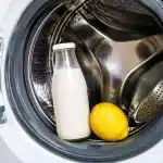 Bouteille de lait et citron posés sur le tambour ouvert d'une machine à laver