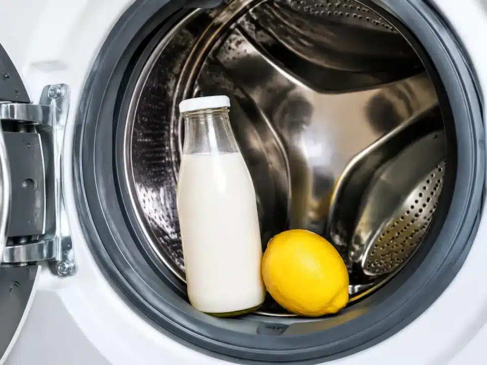 Bouteille de lait et citron posés sur le tambour ouvert d'une machine à laver
