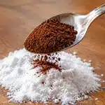 Cuillere versant marc cafe brun sur tas bicarbonate blanc