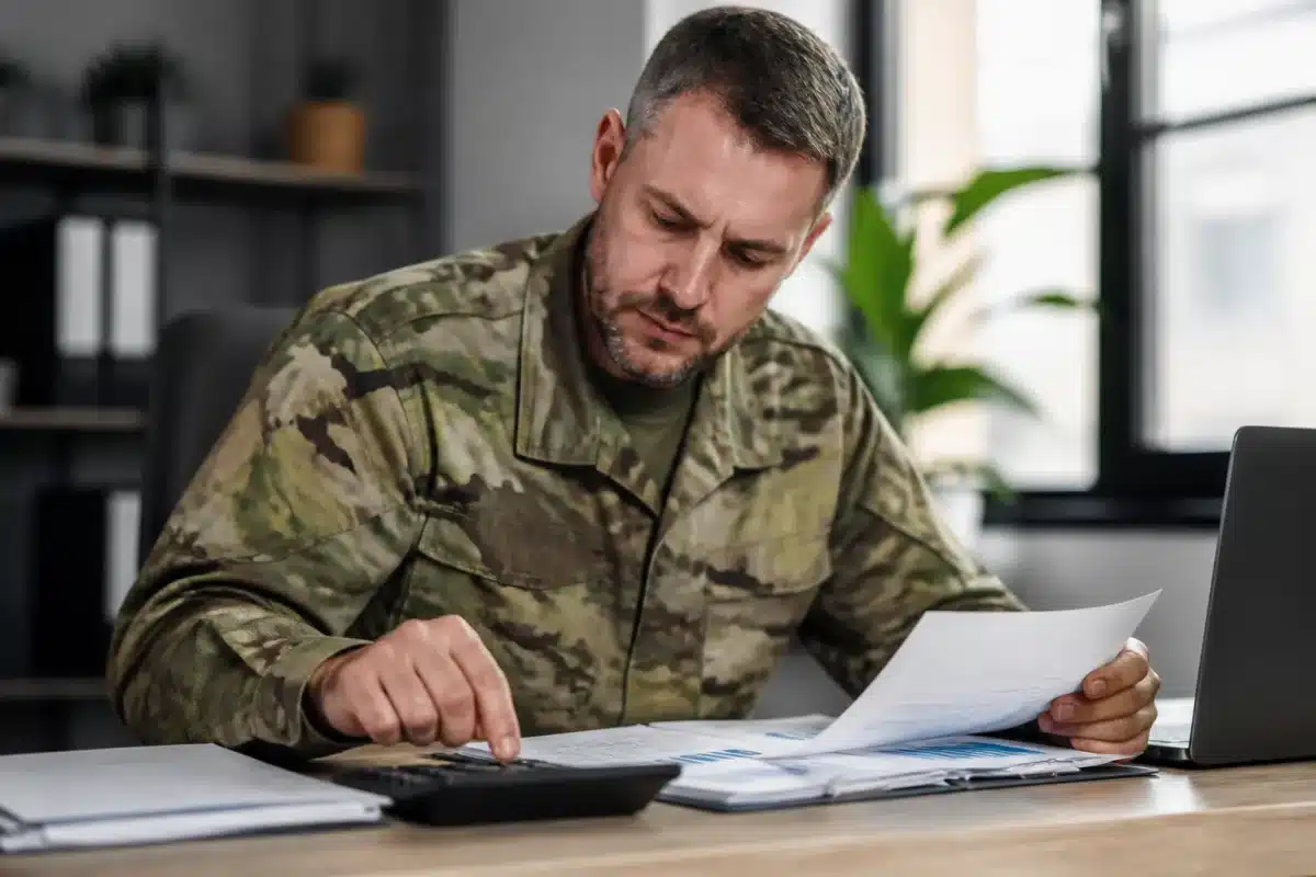 Militaire consultant documents financiers avec calculatrice sur bureau