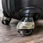 Ruban adhésif enroulé autour de roulettes de valise noire