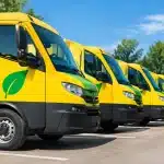 Camions postaux alignes montrant panneaux emissions reduites vertes