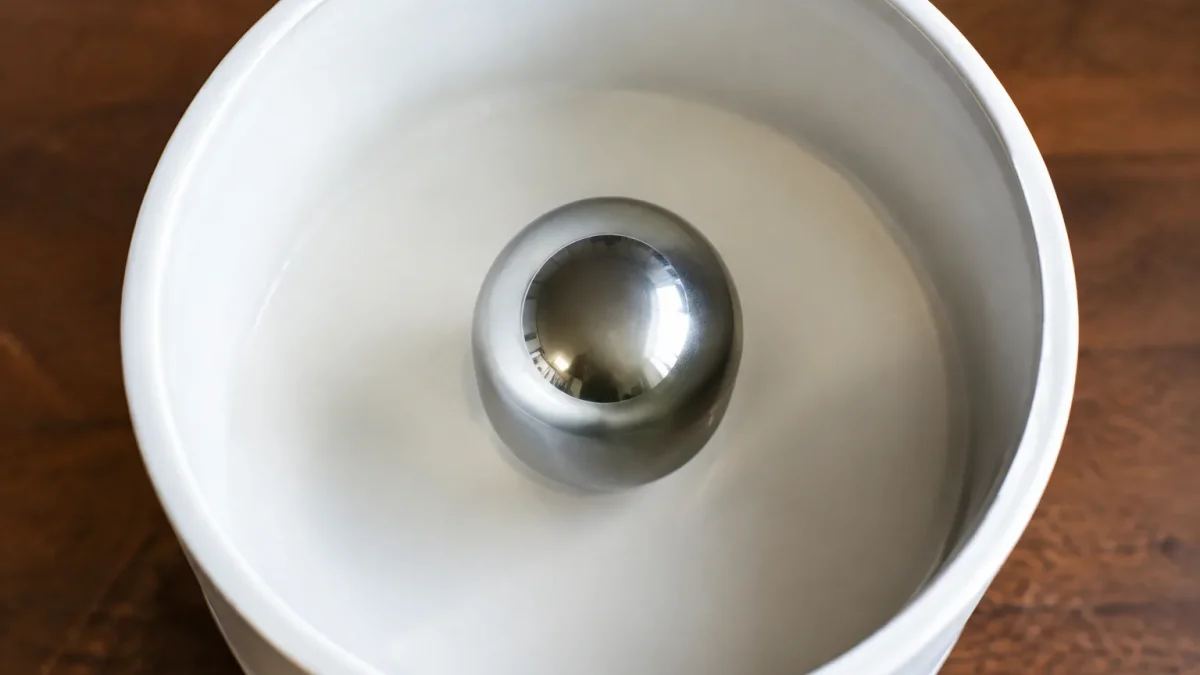 Sphere metallique argentee centree dans tambour blanc