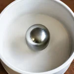 Sphere metallique argentee centree dans tambour blanc