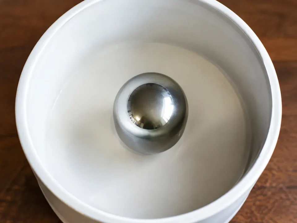 Sphere metallique argentee centree dans tambour blanc