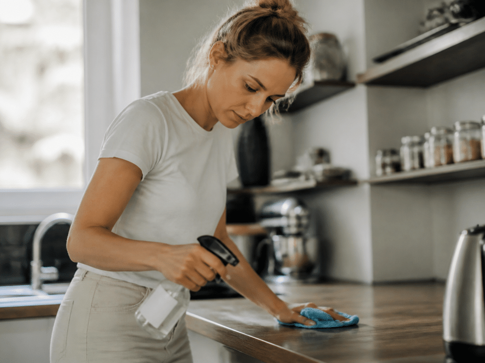 Femme nettoyant comptoir cuisine avec produit spray et chiffon