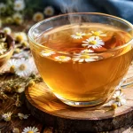 Tasse remplie d'infusion ambree fumante avec petales de camomille